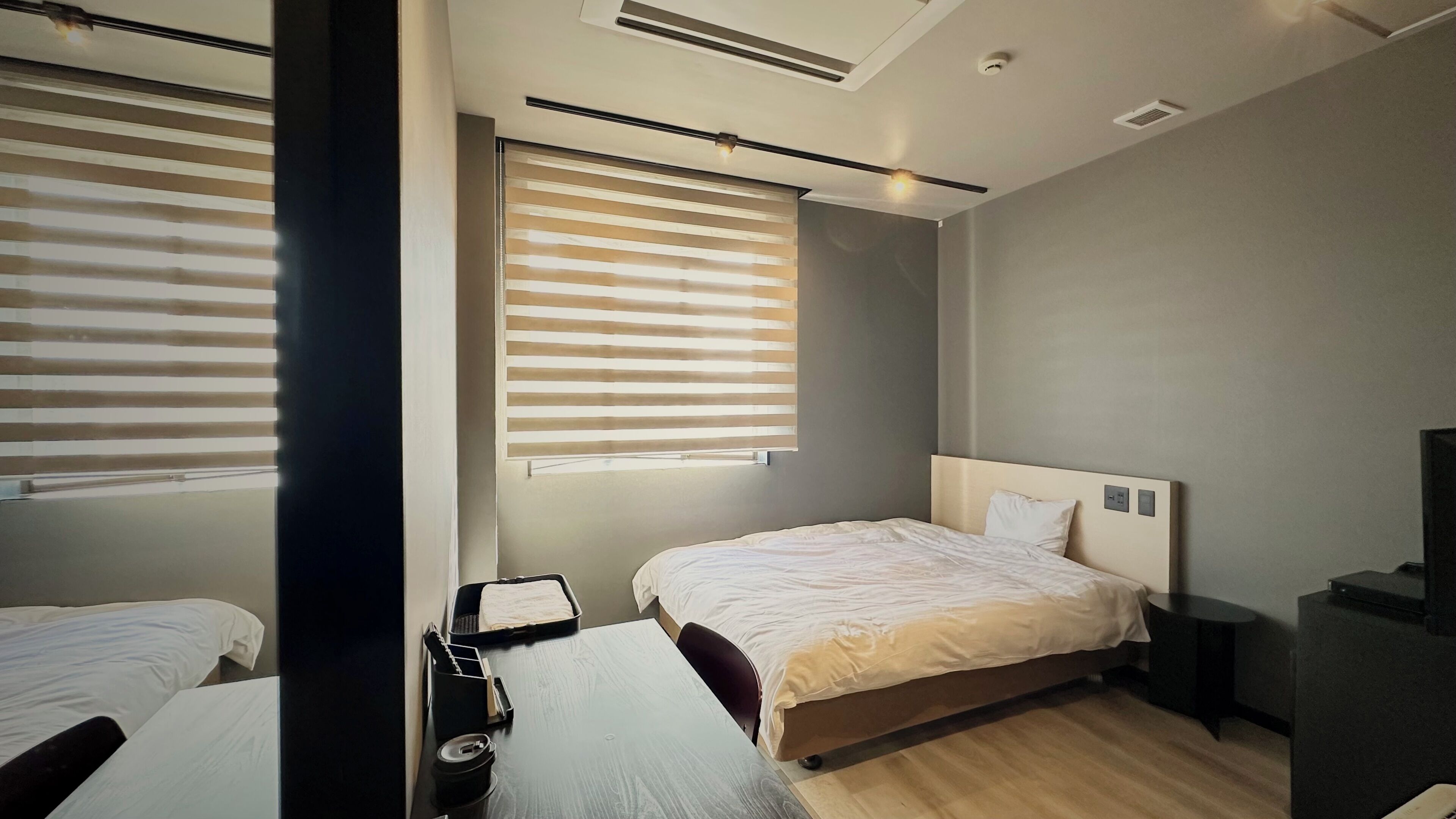 A modern hotel room with a large bed, a desk, and a television.