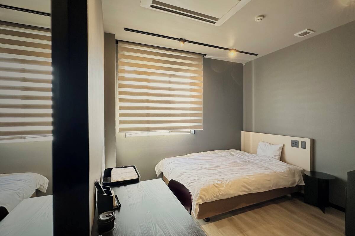 A modern hotel room with a large bed, a desk, and a television.