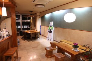 Interior de restaurante con mobiliario de madera, un cartel grande de un personaje y una lámpara colgante.