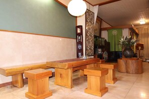 Un espace avec un banc en bois, une table, un vase décoratif et un mur orné d’une horloge et de tableaux encadrés.