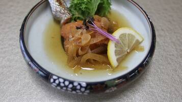 A plate with a fish, lemon, and greens.