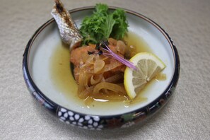 Une assiette avec du poisson, un citron et des légumes verts.