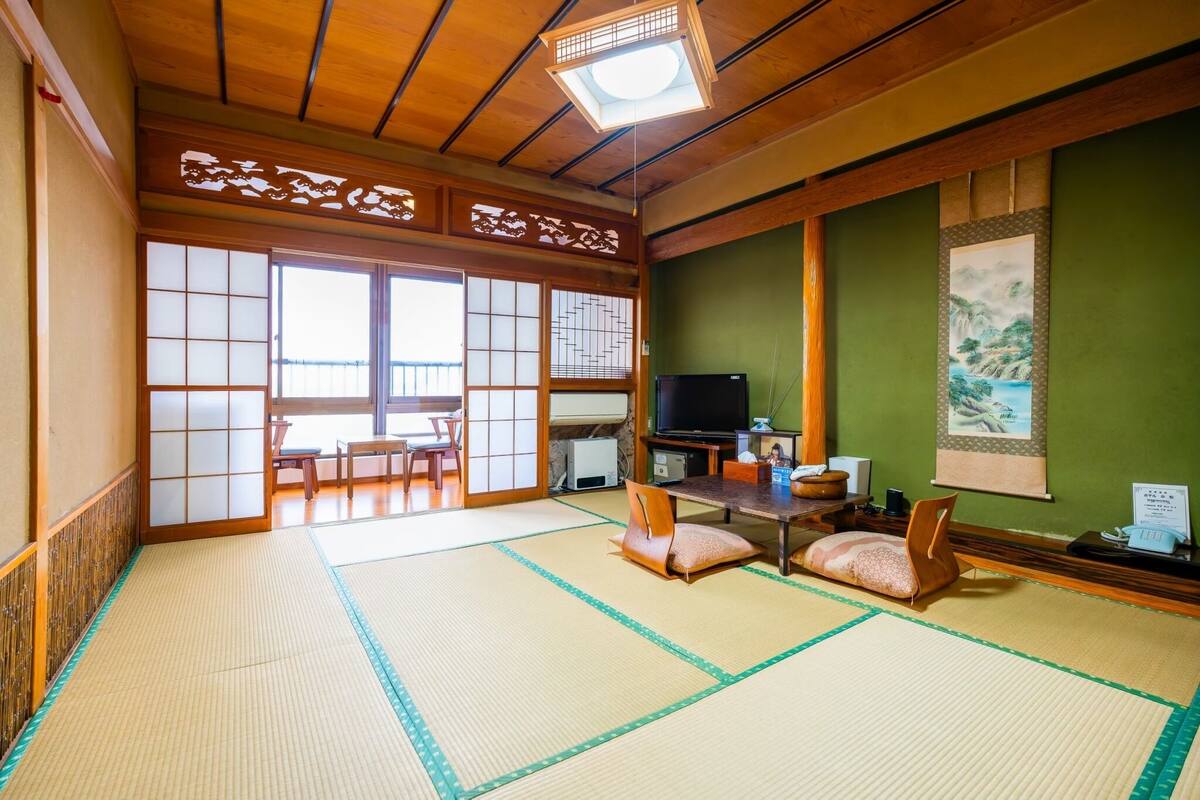 Una habitación japonesa tradicional con suelo de tatami, un televisor y un cuadro en la pared.