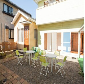 A residential property with a patio area featuring outdoor furniture and a small garden. - Business Ryokan Yokohamaya (Kamisu)