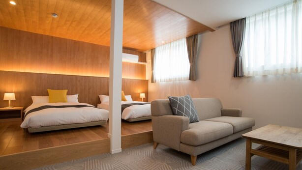 Ein modernes Hotelzimmer mit zwei Betten, einem Sofa und einem kleinen Tisch.