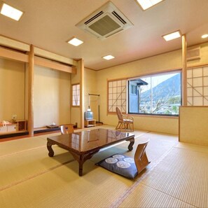 Une pièce de style japonais traditionnel, avec un sol recouvert de tatamis, une table basse et des portes coulissantes.