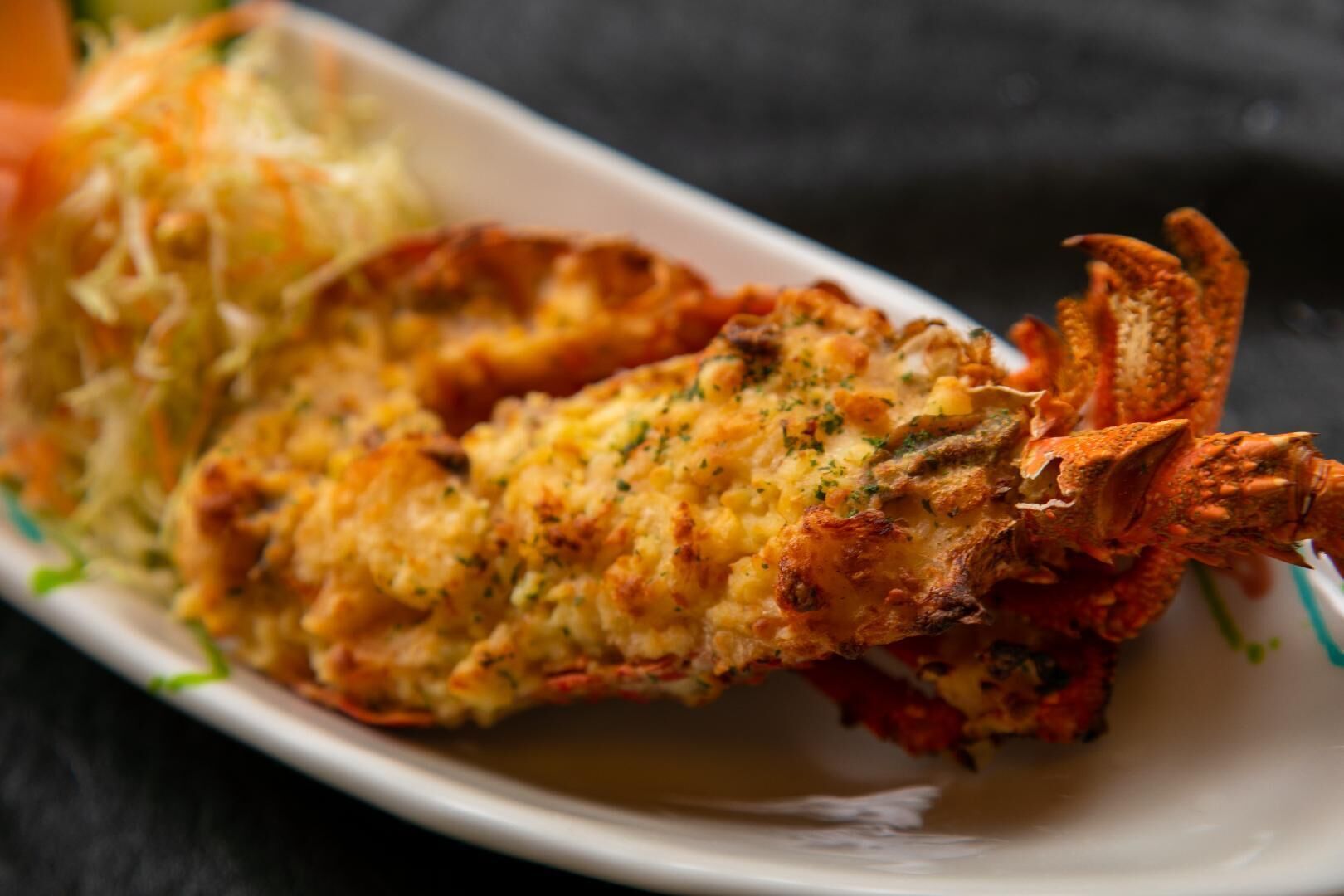 Eine Portion panierten und frittierten Meeresfrüchte, möglicherweise Hummer, auf einem weißen Teller vor dunklem Hintergrund.