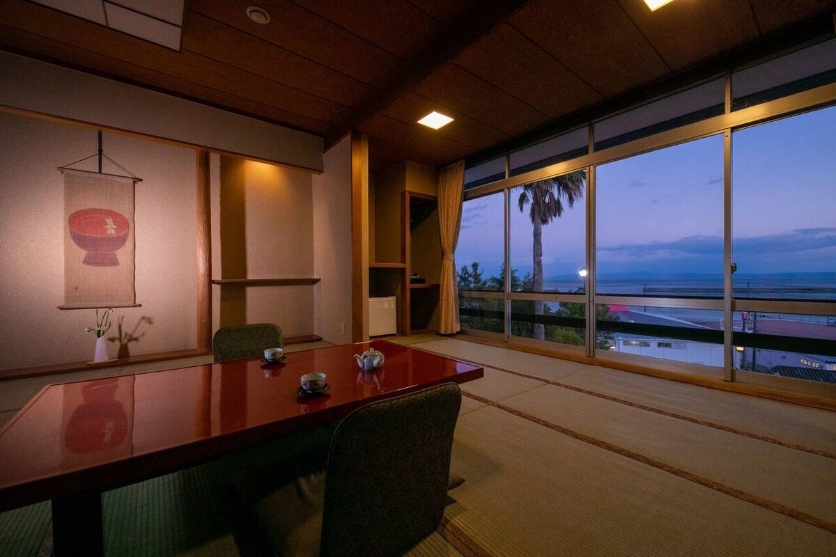 Une pièce avec une grande table, des chaises, un élément décoratif suspendu et une vue sur l’extérieur.