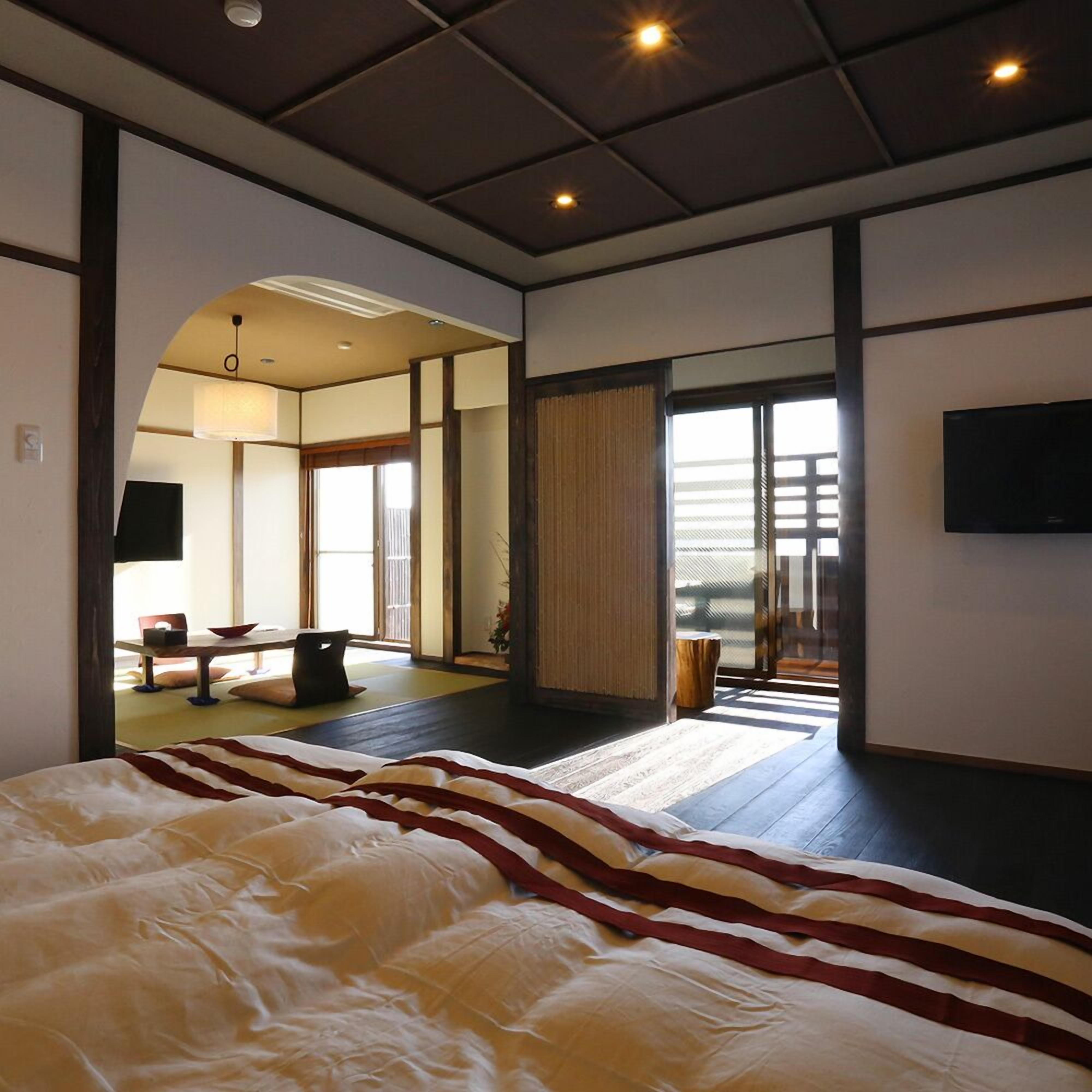 A spacious bedroom with a large bed, a television, and a sliding glass door leading to a balcony.