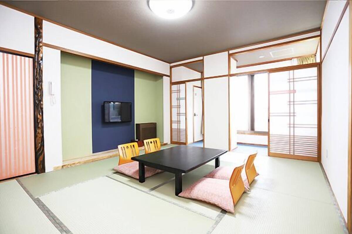 A traditional Japanese room with tatami flooring, a low table, and sliding doors.