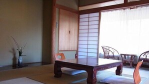 A traditional Japanese room with tatami flooring, a low table, and a sliding door.