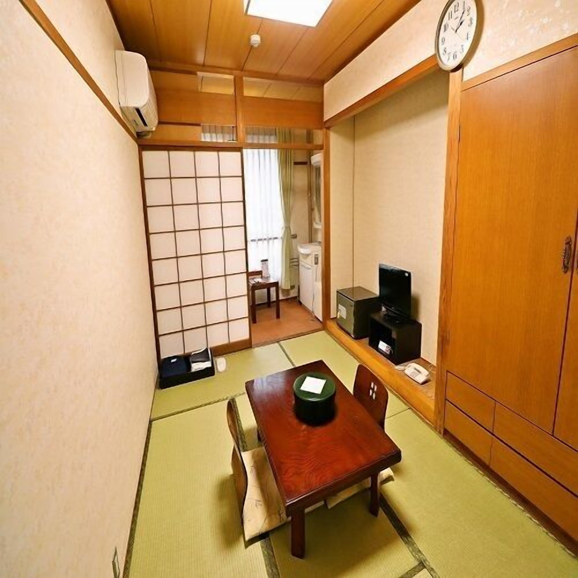 A traditional Japanese room with tatami flooring, a wooden table, a television, and a sliding door.
