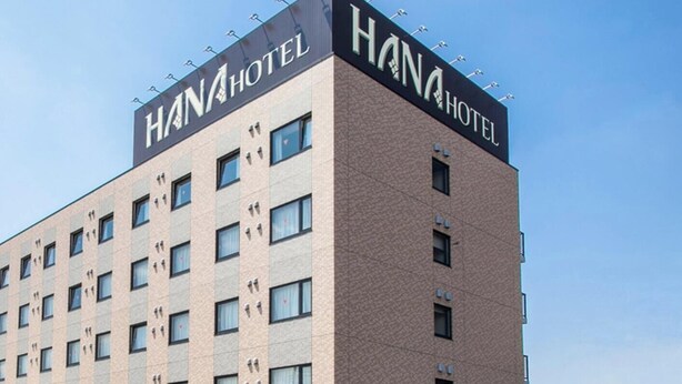Un hôtel moderne, avec une enseigne bien visible sur la façade, portant l’inscription « HANAHOTEL ».