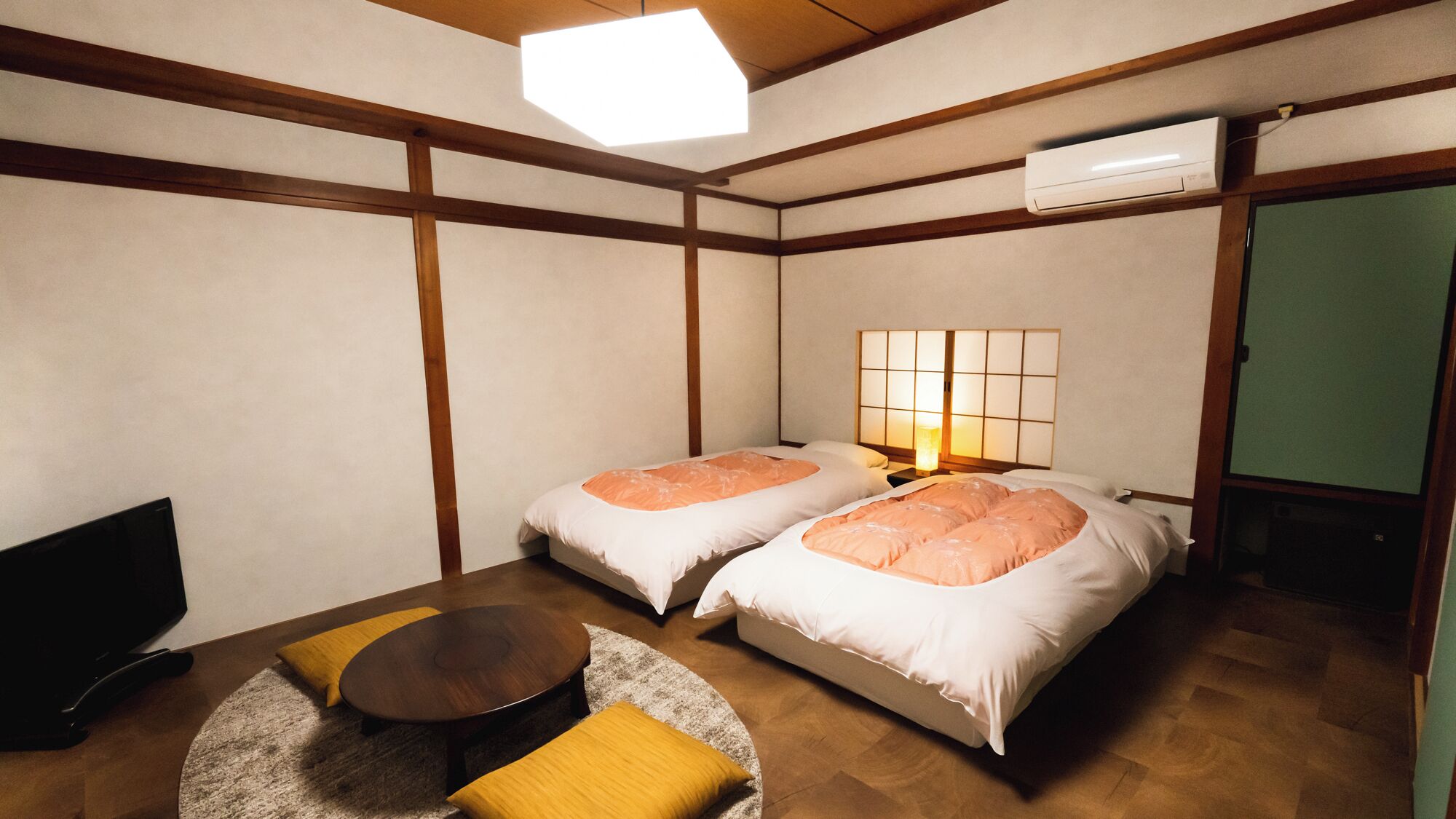 A room with two beds, a small round table, and a television.