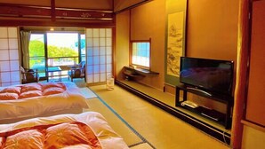 A traditional Japanese-style room with tatami flooring, a bed, a television, and a sliding door leading to an outdoor area.