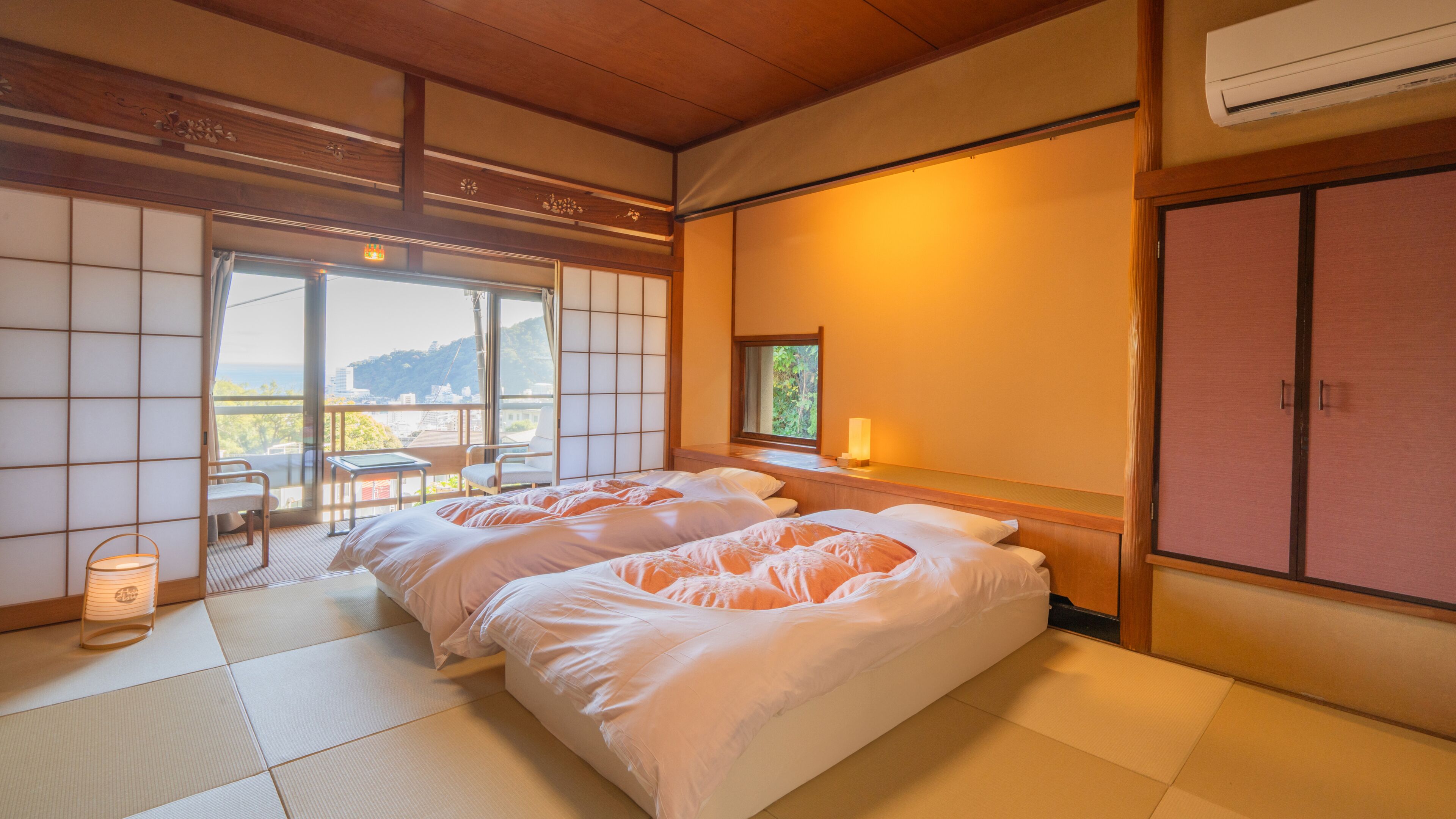 A hotel room with tatami flooring, a balcony with a view, and a traditional Japanese-style bed.