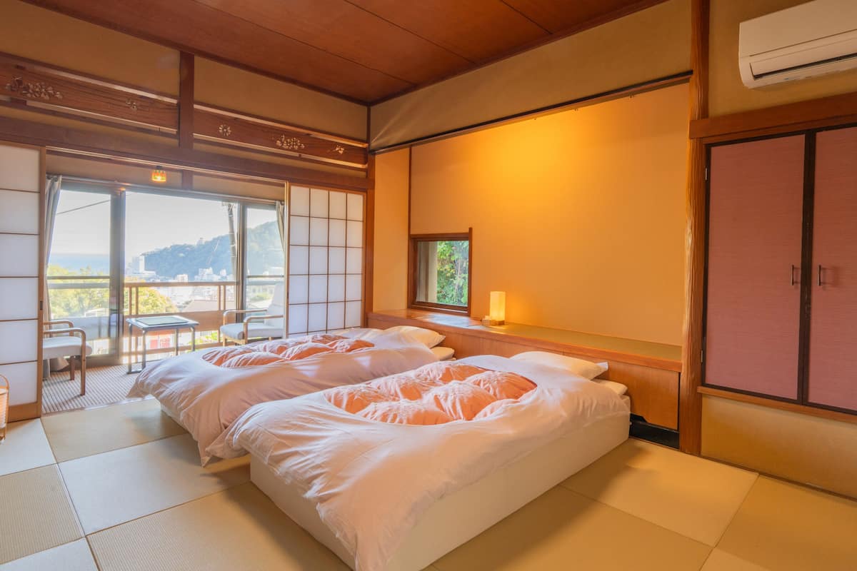 A hotel room with tatami flooring, a balcony with a view, and a traditional Japanese-style bed.