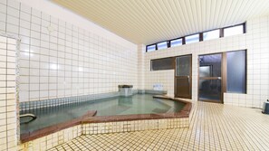 Un'ampia piscina interna con pareti piastrellate e soffitto inclinato.