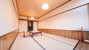 A traditional tatami mat room with a low table, a television, and a wooden panel wall. - Marue Honkan (Hitoyoshi)