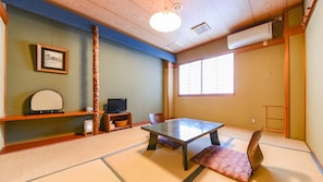Une pièce de style japonais traditionnel, avec un sol recouvert de tatamis, une table basse, un téléviseur et une fenêtre dotée de panneaux coulissants en papier de riz (shoji).