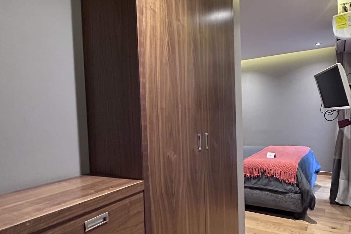 Un dormitorio con armario, cama y escritorio con computadora.