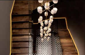 Una escalera con una lámpara de araña moderna y baldosas de suelo estampadas.