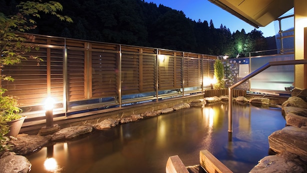 A tranquil outdoor pool area with wooden fencing, a stone pathway, and a wooden deck. - New Ougiya (Fukushima)