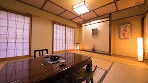 Una habitación japonesa tradicional con suelo de tatami, una mesa baja y puertas correderas.