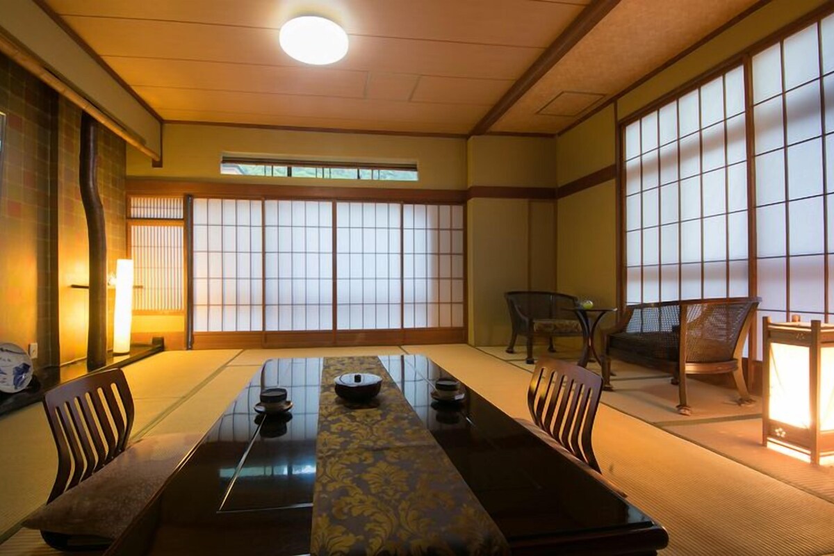 Une pièce de style japonais traditionnel, avec un sol recouvert de tatamis, une table basse agrémentée d’un chemin de table décoratif et des portes coulissantes en papier de riz (shoji).