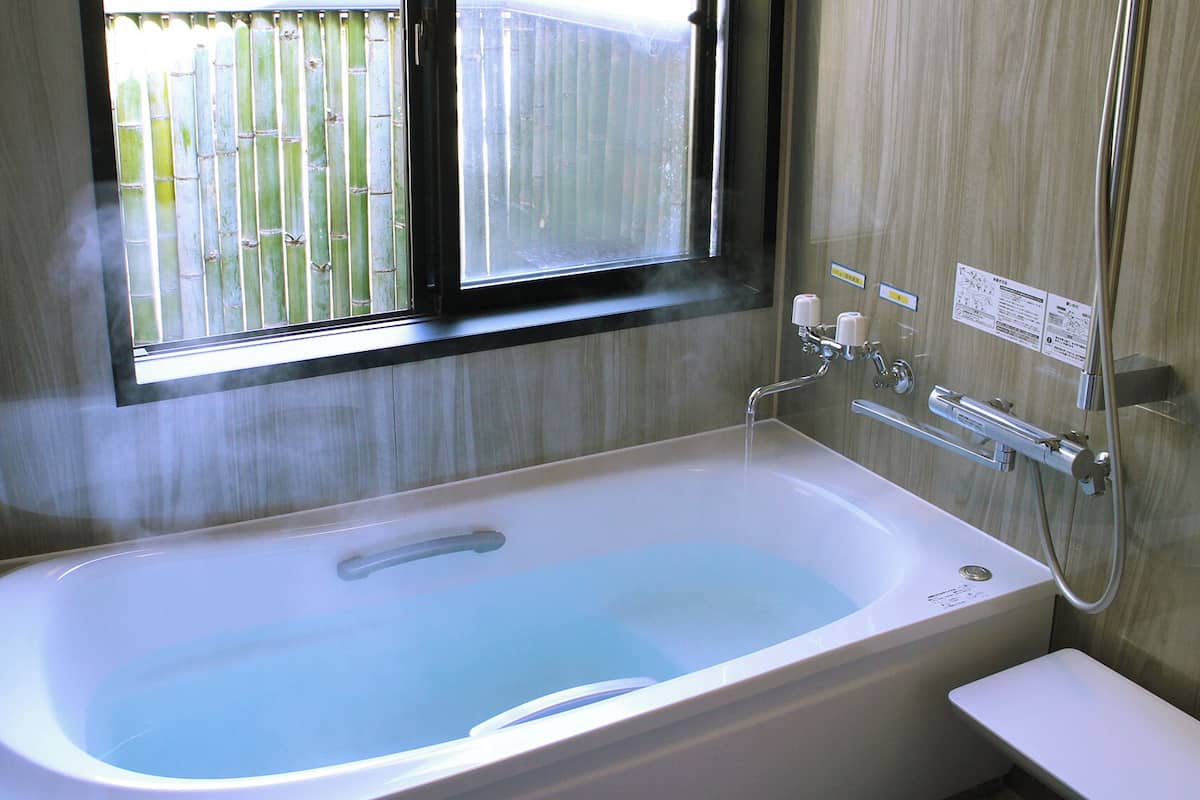 A bathroom with a bathtub, a window, and a shower.