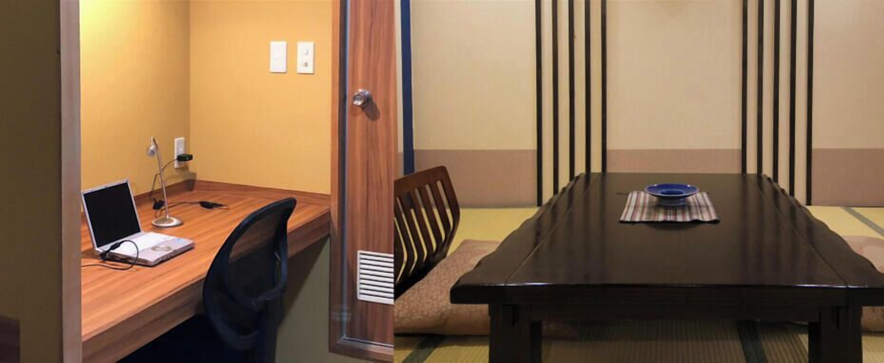 A conference room with a wooden table, a laptop, a chair, and a sofa.