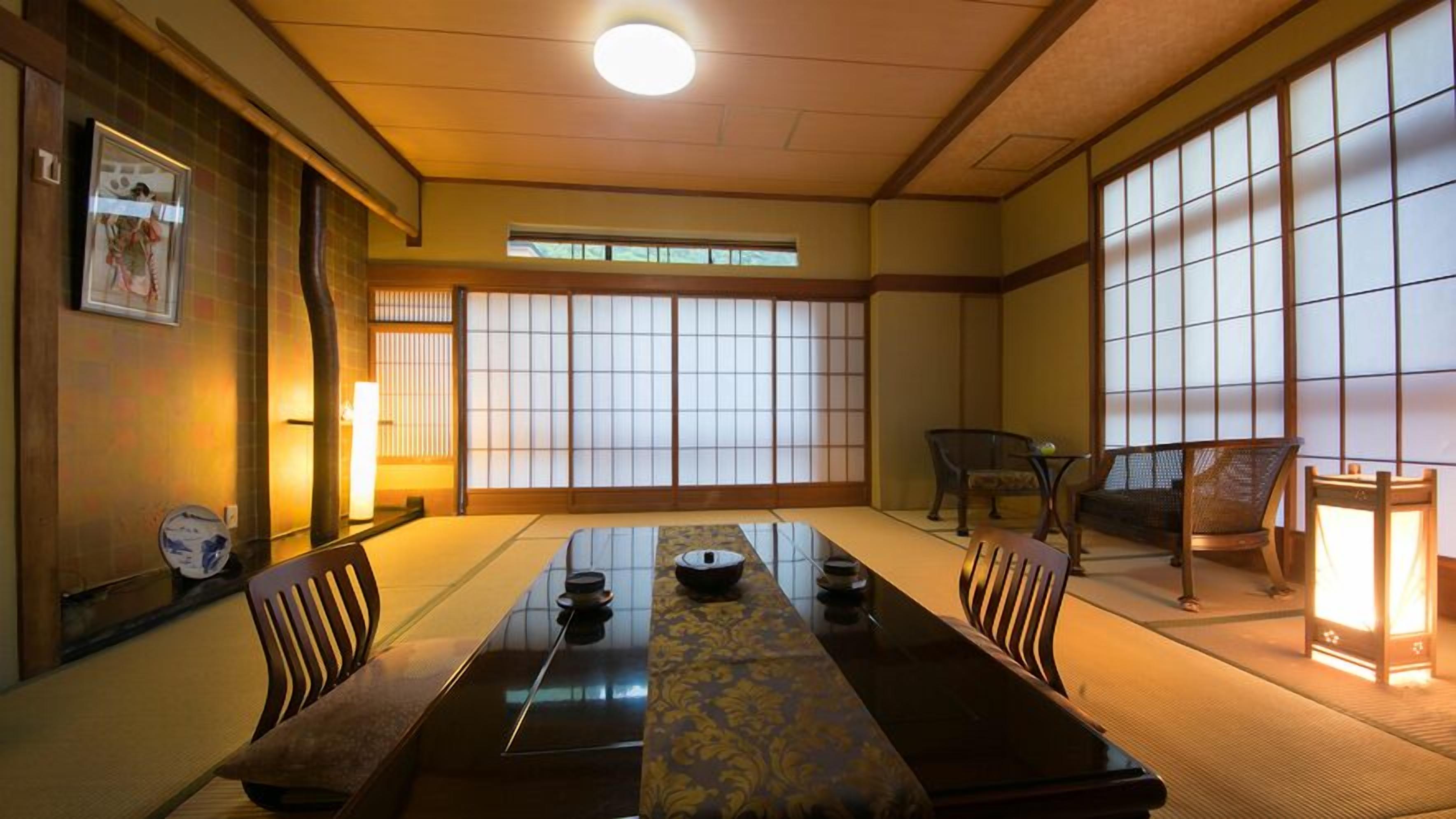 A traditional Japanese-style room with tatami flooring, a low table with a decorative runner, and sliding shoji doors.