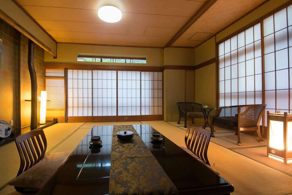 A traditional Japanese-style room with tatami flooring, a low table with a decorative runner, and sliding shoji doors.