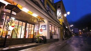 A street view at night with a restaurant featuring large glass windows and illuminated signage. - New Ougiya (Fukushima)