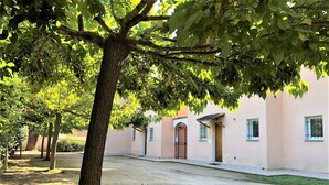 A courtyard with a tree, a building with a tiled roof, and a paved walkway. - Charming *** villa with heated pool, near downtown (porto vecchio)