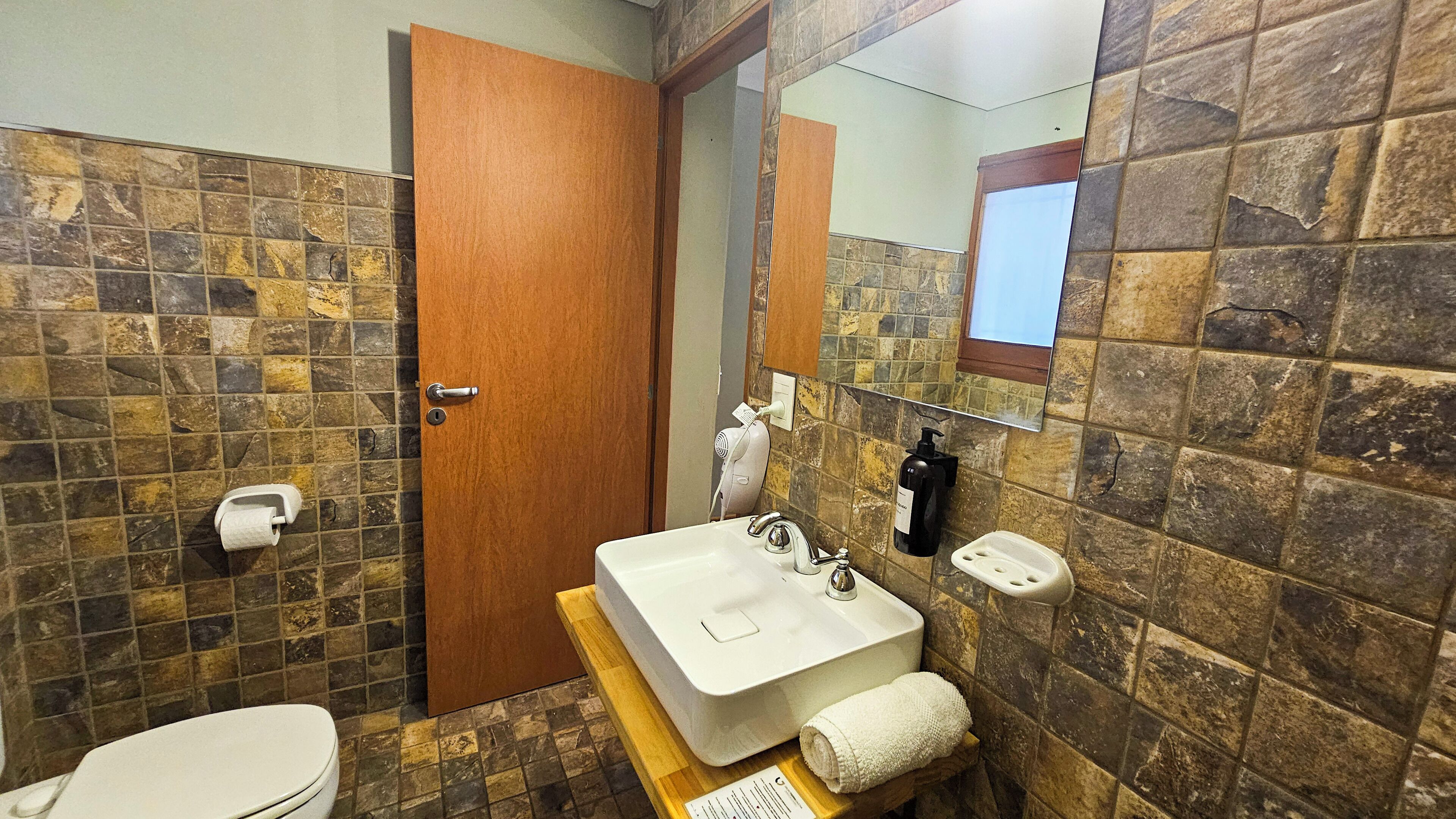 A bathroom with a white sink, a mirror, a towel, and a toilet.