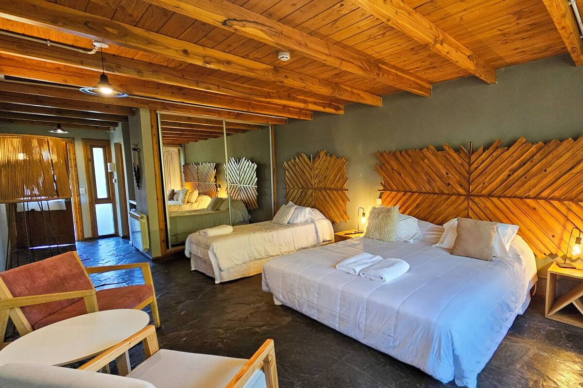 Une chambre d’hôtel avec deux lits, un plafond en bois et un grand panneau décoratif mural.
