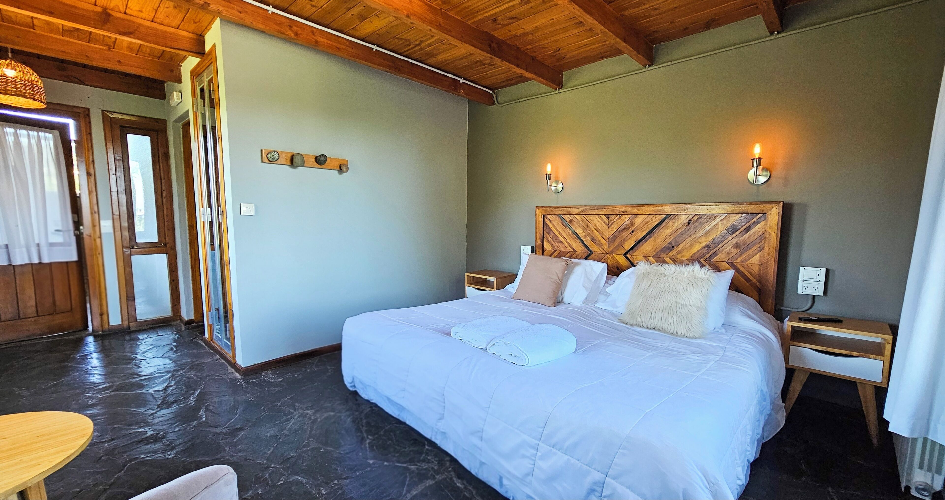 A bedroom with a bed, wooden headboard, bedside tables, and a stone floor.