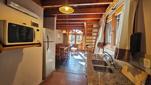 Una cocina equipada con microondas, refrigerador, encimera de granito, lavamanos y vigas de madera.
