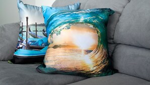 A gray sofa with two decorative pillows, one with a blue and white design and the other with a wave and sunset design. - Murano Elite Luxury Bocagrande (Cartagena)