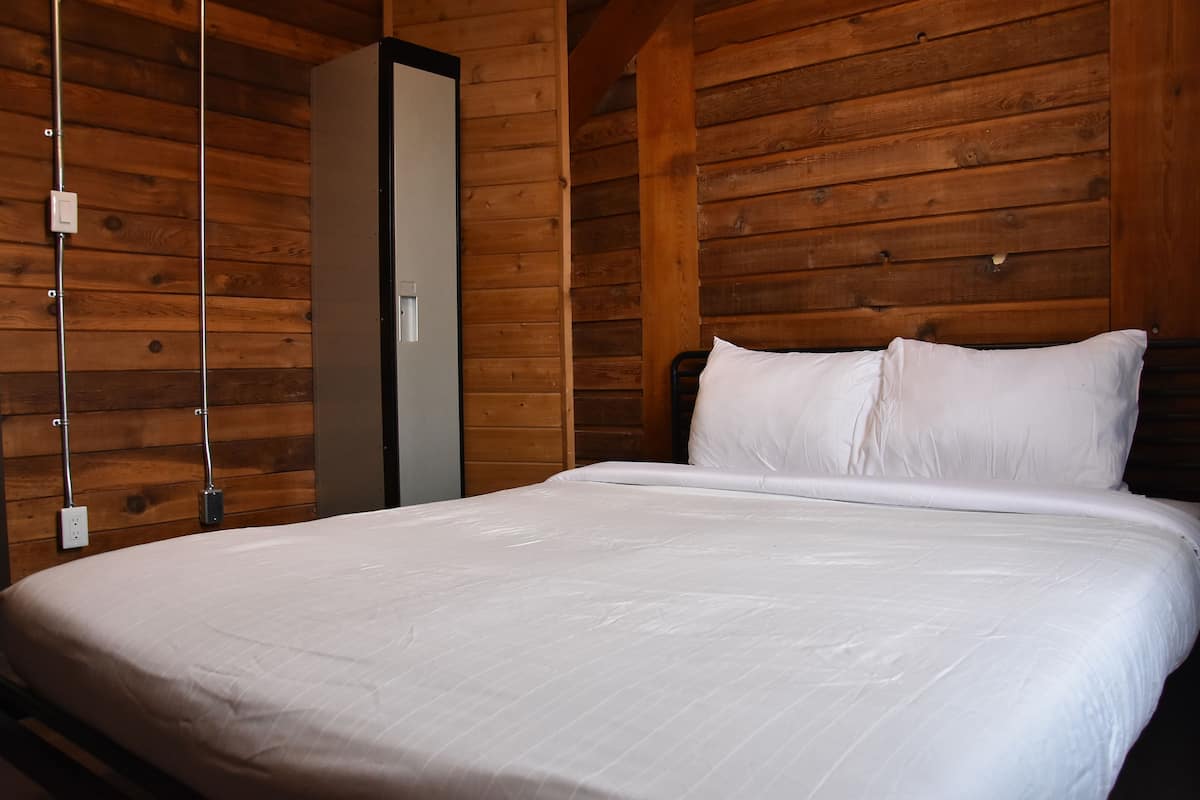 A wooden-paneled room with a bed, a wardrobe, and a hanging light fixture.