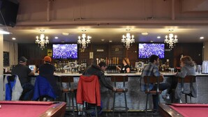 A bar area with multiple seating arrangements, a pool table, and two televisions mounted on the wall. - Party Hostel- Canmore Hotel Hostel (Canmore)