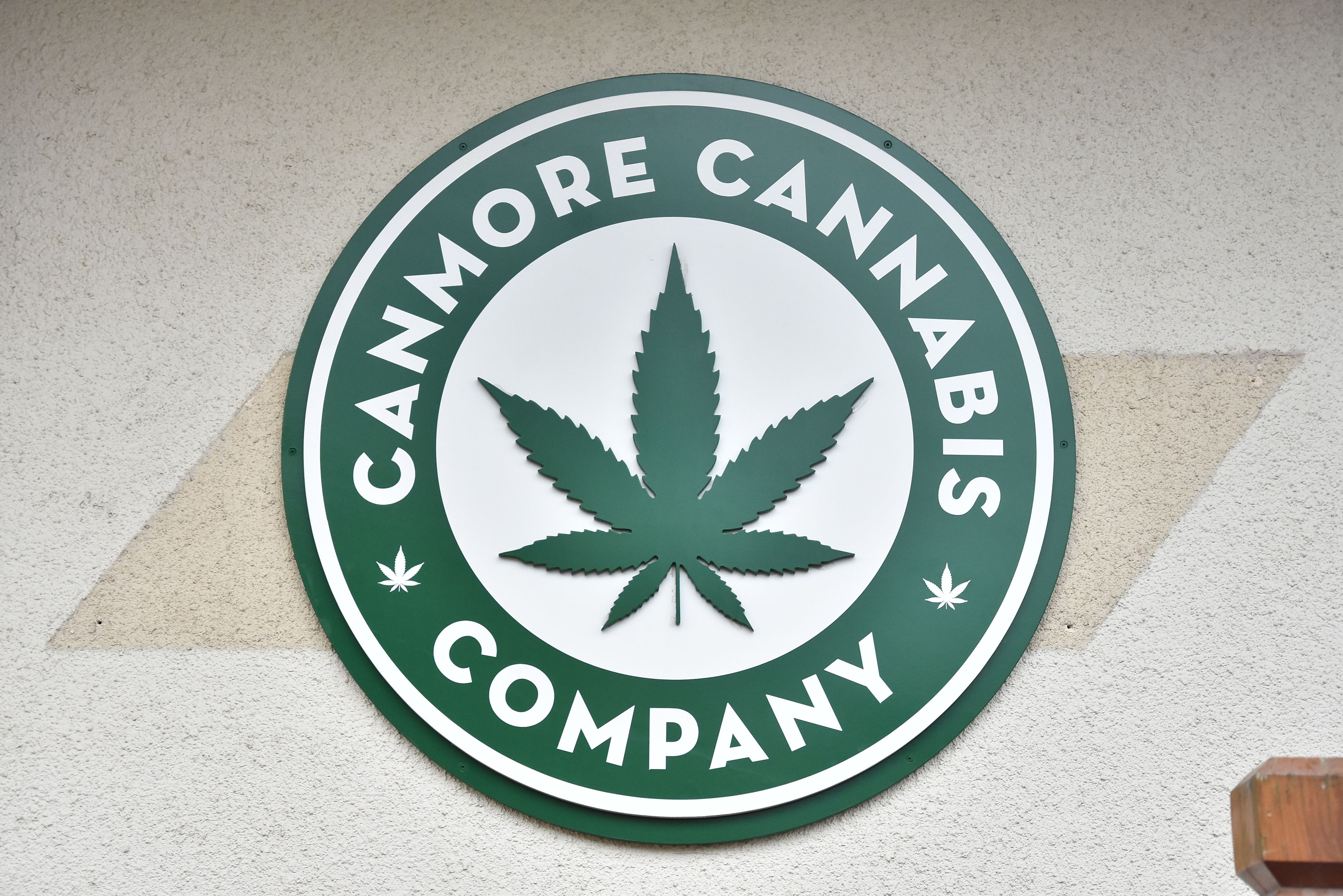 A circular sign with the text "Cannmore Cannabis Company" and a cannabis leaf symbol.