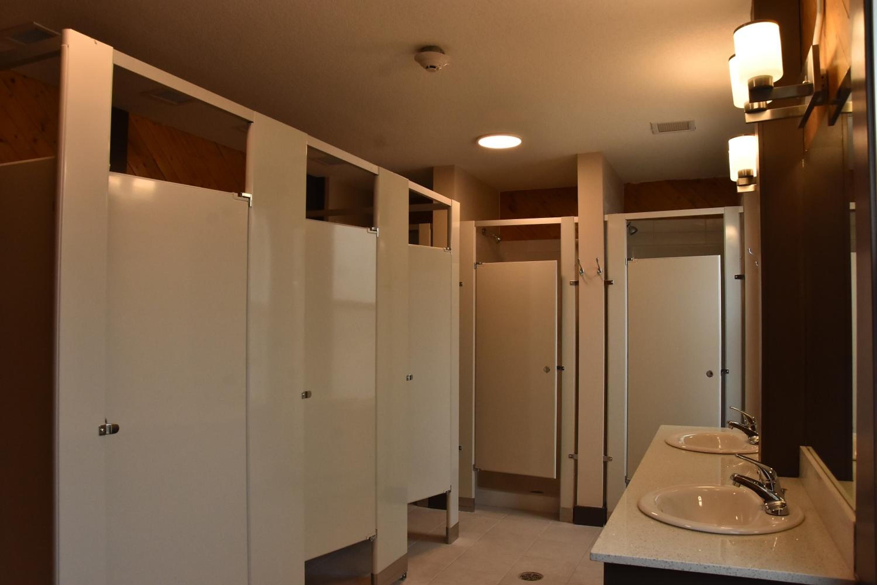 Un baño de hotel con dos lavamanos, un espejo y una cabina de ducha.