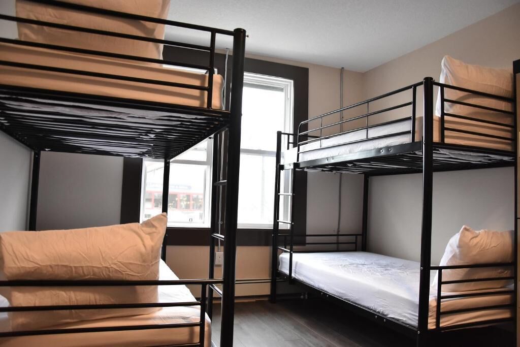 A dormitory room with bunk beds, a window, and a view of the outside.