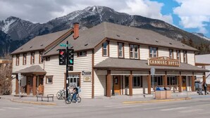 A two-story building with a sign reading "CANMORE HOTEL" and a mountain backdrop. - Party Hostel- Canmore Hotel Hostel (Canmore)