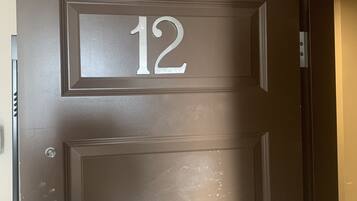 A brown door with the number 12, a metal handle, and a small window.