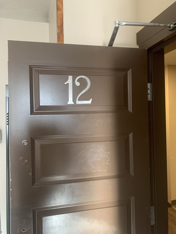 A brown door with the number 12, a metal handle, and a small window.