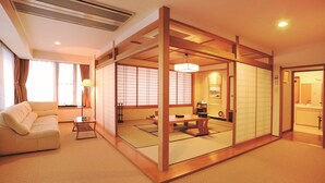 Une pièce de style japonais traditionnel, avec un sol recouvert de tatamis, une table basse, un canapé et des portes coulissantes.
