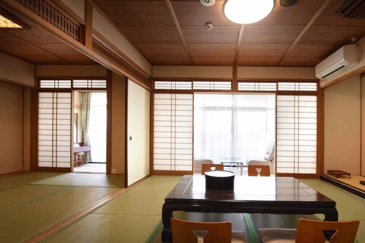 A traditional Japanese room with tatami flooring, a low table, and sliding doors.